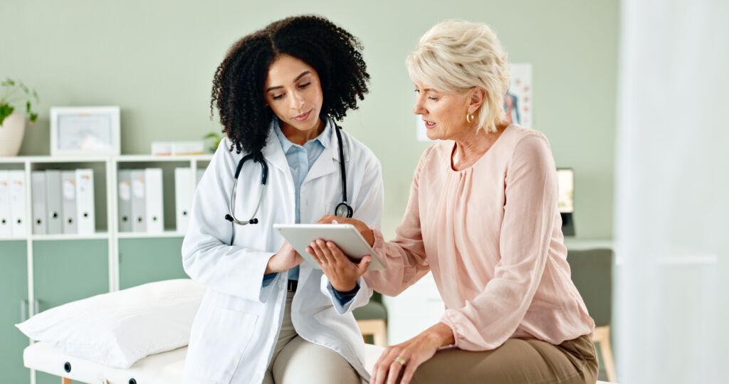 Doctor showing clinical trial information to a female patient on a tablet in a medical office