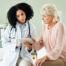 Doctor showing clinical trial information to a female patient on a tablet in a medical office