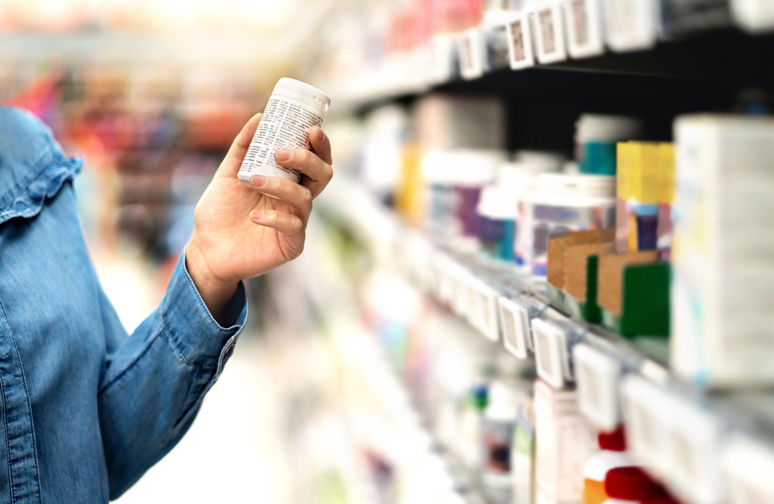 Customer in pharmacy holding medicine bottle. Woman reading the